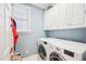Functional laundry room with washer, dryer, storage cabinets, and natural light at 104 Barnes Spring Ct, Cary, NC 27519