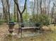 Tranquil backyard seating area with a decorative bench and potted greenery in a natural setting at 105 Aberson Ct, Cary, NC 27519