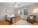 This cozy bedroom features hardwood floors, a wooden bed frame, an armchair, and large window with lots of natural light at 105 Aberson Ct, Cary, NC 27519