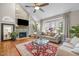Cozy living room features a stone fireplace, ceiling fan and hardwood flooring at 105 Aberson Ct, Cary, NC 27519