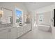 Bright bathroom with double sink, white cabinets, tub, and ample natural light at 109 W Markham Ave, Durham, NC 27701