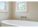 Close-up of a modern soaking tub with chrome faucet and natural light from two windows at 109 W Markham Ave, Durham, NC 27701