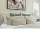 Bright bedroom featuring a plush bed with decorative pillows, neutral walls, and a framed art piece above the headboard at 109 W Markham Ave, Durham, NC 27701