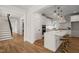 Stylish white kitchen featuring an island, brass barstools, stainless appliances, and hardwood floors at 109 W Markham Ave, Durham, NC 27701
