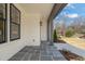 Charming covered porch with bluestone tile flooring, gray columns, and stylish exterior lighting fixture at 109 W Markham Ave, Durham, NC 27701