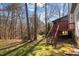 Green and shady backyard featuring a tall red-stained wooden deck, stairs and wooded backdrop at 12 Citation Dr, Durham, NC 27713