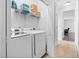 Well-lit laundry room with white washer, dryer, wire shelves, and doorway to hallway at 16 Eagle Swoop St, Zebulon, NC 27597