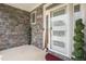 Close-up of front door with glass accents, stylish stone wall, and manicured shrubs at 206 Hamby St, Clayton, NC 27520