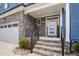 A welcoming front porch with stone stairs and iron railings leading to a front door with stone and siding at 206 Hamby St, Clayton, NC 27520