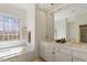 Bright bathroom featuring a soaking tub, double vanity with gold fixtures, and a large window at 2602 Vintage Hill Ct, Durham, NC 27712