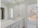 Bright bathroom featuring double sinks, white cabinets, and a window with a wooded view at 2602 Vintage Hill Ct, Durham, NC 27712