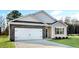 View of a tan single-story home featuring a two-car garage, black accents, and a well-kept lawn at 31 Black Creek Dr, Lillington, NC 27546