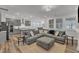 Open-concept living room features a large gray sectional sofa, wood floors, and seamlessly connects to the kitchen at 372 Natsam Woods Way, Wake Forest, NC 27587