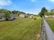 Image shows the exterior and large, grass-covered backyard area with a chain-link fence at 4 Hannah Ct, Durham, NC 27713