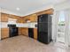 Efficient kitchen featuring wooden cabinets, black appliances, and a back door with window at 4 Hannah Ct, Durham, NC 27713