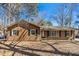 Inviting one-story home featuring a brick and wood facade, surrounded by mature trees and a well-maintained yard at 411 Colony Woods Dr, Chapel Hill, NC 27517