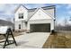 Two-story home featuring light gray siding, attached garage, and a neatly landscaped yard on a bright, sunny day at 44 Rolling Banks Dr, Louisburg, NC 27549