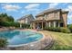 A luxury brick home showcasing a pool with a large patio, an outdoor seating area, and lush landscaping at 5026 Clyden Cv, Raleigh, NC 27612