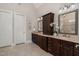 Elegant bathroom featuring a dual vanity with dark wood cabinets, granite countertops, decorative lighting and two mirrors at 5026 Clyden Cv, Raleigh, NC 27612