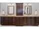 Spacious bathroom features a dual vanity with dark wood cabinets, granite countertops and decorative lighting with a central tower cabinet at 5026 Clyden Cv, Raleigh, NC 27612