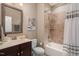 Well-lit bathroom with modern vanity, tiled shower with tub, and decorative mirror at 5026 Clyden Cv, Raleigh, NC 27612