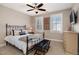 A cozy bedroom with a wrought iron bed frame, ceiling fan, bench and an abundance of light at 5026 Clyden Cv, Raleigh, NC 27612