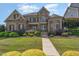 Stately stone and brick home with manicured landscaping and a sidewalk leading to the front entrance at 5026 Clyden Cv, Raleigh, NC 27612