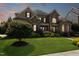 Exterior view of a stone and brick home with a manicured lawn and landscaping at sunset at 5026 Clyden Cv, Raleigh, NC 27612