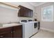 Well-equipped laundry room features a sink, built-in cabinets, and modern washer and dryer units with a window at 5026 Clyden Cv, Raleigh, NC 27612