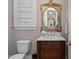 Traditional powder room with a decorative mirror, dark wood vanity, white countertop, and a window with plantation shutters at 5026 Clyden Cv, Raleigh, NC 27612