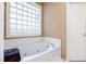 Bathroom featuring a large soaking tub, glass block window, and white tile at 715 Thompson Rd, Garner, NC 27529