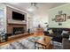 Cozy living area featuring a brick fireplace, hardwood floors, and a comfortable sectional sofa at 715 Thompson Rd, Garner, NC 27529