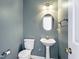 A well-lit half bath featuring a pedestal sink, toilet, and classic fixtures in a calming color palette at 725 Littleleaf Ct, Holly Springs, NC 27540