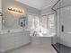 Bright bathroom featuring a soaking tub, double vanity, and a walk-in shower with subway tile at 725 Littleleaf Ct, Holly Springs, NC 27540