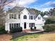 Charming two-story white home with a black roof, blooming trees, and manicured landscaping at 725 Littleleaf Ct, Holly Springs, NC 27540