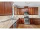 Traditional kitchen featuring stainless steel appliances and granite countertops, complemented by wood cabinets and flooring at 725 Littleleaf Ct, Holly Springs, NC 27540