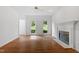 Living room with a fireplace, hardwood floors, white walls, and a ceiling fan, providing a warm ambiance at 725 Littleleaf Ct, Holly Springs, NC 27540