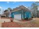 Side exterior view featuring a teal siding, attached garage, lush landscaping, and inviting curb appeal at 725 Thompson Rd, Garner, NC 27529