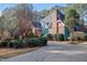 A beautifully landscaped home exterior with a brick chimney and winding driveway, surrounded by mature trees at 725 Thompson Rd, Garner, NC 27529
