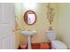 Cozy powder room featuring a pedestal sink, round mirror, and decorative wall art at 725 Thompson Rd, Garner, NC 27529