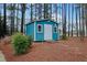 Charming teal shed nestled among towering trees, offering extra storage with a rustic touch to the landscape at 725 Thompson Rd, Garner, NC 27529