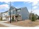 Side view of a modern townhome with blue siding and a well-manicured lawn on a sunny day at 1000 Pyrenees Way, Cary, NC 27519