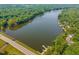 Stunning aerial view of a lake surrounded by lush green trees and a paved road with a bridge at 101 Rustic Wood Ln, Cary, NC 27518