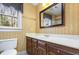 Bright bathroom with a window, vanity, toilet, mirror, and striped wallpaper design at 101 Rustic Wood Ln, Cary, NC 27518