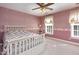 Cozy bedroom features pink wallpaper and trim, a ceiling fan and a white bed frame at 101 Rustic Wood Ln, Cary, NC 27518