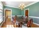 Elegant dining room with a chandelier, hardwood floors, and green walls creating a sophisticated ambiance at 101 Rustic Wood Ln, Cary, NC 27518