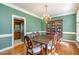 Green dining room with hardwood floors, chandelier, table with six chairs, and china cabinet at 101 Rustic Wood Ln, Cary, NC 27518