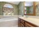 A lavish soaking tub with large window sits next to a wooden vanity in the main bath at 101 Rustic Wood Ln, Cary, NC 27518