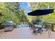 Outdoor deck featuring a grill, dining area, and views of the beautiful backyard pool and lush greenery at 1011 Oxbow Crossing Rd, Chapel Hill, NC 27516