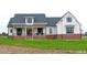 Attractive two-story farmhouse with a covered front porch and brick foundation, complemented by black window frames and a welcoming double-door entry at 107 Crescent Hill Ln, Rougemont, NC 27572
